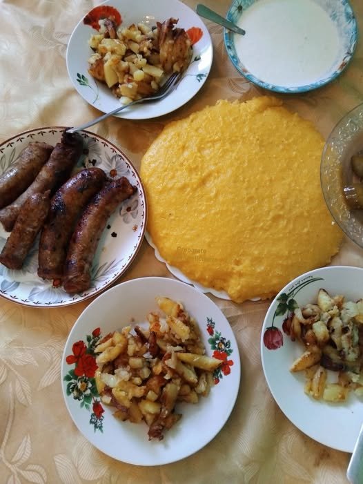 Sarmale cu varză proaspătă și mămăligă cu brânză și smântână – tradiție, gust și confort în sezonul rece
Introducere: gustul iernii în farfurie

Nu știu cum sunteți voi, dar pentru mine, iarna nu este completă fără aroma intensă a sarmalelor proaspete, iar atunci când varza murată nu este încă pregătită, soluția salvatoare este reprezentată de sarmalele cu varză proaspătă, pregătite cu grijă, răbdare și ingrediente atent alese, care transformă fiecare masă într-un adevărat festin. Alături de ele, mămăliga cu brânză și smântână joacă rolul de companion perfect, completând textura, gustul și savoarea, astfel încât întreaga experiență culinară să fie echilibrată, reconfortantă și memorabilă, oferind acel sentiment inconfundabil de „acasă” care transformă fiecare zi friguroasă într-un moment plin de căldură.

De ce sarmalele cu varză proaspătă sunt atât de speciale

Sarmalele cu varză proaspătă reprezintă o adevărată soluție pentru mesele de iarnă, deoarece ele combină avantajele tradiției cu practicitatea ingredientelor disponibile, oferind un gust bogat, suculent și aromat, chiar și atunci când fermentarea naturală a verzei murate nu este încă finalizată. Varza proaspătă permite ca aromele cărnii, orezului și condimentelor să se dezvolte armonios, fără a fi dominată de aciditatea specifică verzei murate, iar textura frunzelor, dacă este opărită corect, devine suficient de elastică pentru rulare și suficient de fragede pentru a se îmbiba cu sosul savuros.

Această variantă de sarmale este apreciată nu doar pentru gust, ci și pentru versatilitate: poate fi adaptată în funcție de preferințe, fie că doriți o umplutură mai bogată în carne, mai ușoară, dietetică sau chiar de post, folosind combinații de legume, ciuperci și orez. În plus, sarmalele cu varză proaspătă se păstrează excelent, fiind ideale pentru porții mari, mese în familie sau pregătirea în avans pentru zilele ocupate.

Alegerea și pregătirea verzei proaspete

Sezonul rece aduce provocarea de a găsi varză proaspătă potrivită, însă alegerea corectă este esențială pentru rezultate excelente. Căpățâna trebuie să fie bine legată, cu frunze elastice, fără pete sau zone uscate, iar nervurile groase trebuie subțiate pentru rulare ușoară. Dimensiunea medie este cea mai potrivită, iar culoarea deschisă indică frăgezime și gust plăcut.

Opărirea corectă a frunzelor este pasul decisiv: apa trebuie să fie bine clocotită, frunzele introduse treptat, cu un strop de sare, și lăsate să se scurgă bine după ce sunt frăgezite, pentru a preveni ruperea lor în timpul rulării.

Umplutura perfectă pentru sarmale cu varză proaspătă

Umplutura combină carne de porc și vită pentru un echilibru între grăsime și structură, ceapă călită lent pentru dulceață naturală și orez spălat și ușor călit, care ajută la legarea compoziției. Condimentele – sare, piper, boia dulce, cimbru și dafin – trebuie integrate uniform, iar frământarea ușoară a compoziției ajută la obținerea unei umpluturi suculente, dar nu prea compacte.

Pentru cei care preferă opțiuni mai ușoare sau de post, carnea poate fi înlocuit cu ciuperci, legume sau cereale, iar compoziția obținută va avea în continuare savoare și textură plăcută.

Sosul și rolul lui în aroma finală

Sosul pentru sarmale cu varză proaspătă este baza care leagă aromele: suc de roșii sau pastă diluată, cu puțin borș sau zeamă de lămâie, după preferință, pentru a echilibra gustul și a compensa lipsa acidității naturale. Stratul de varză tocată pe fundul vasului și între rânduri ajută la distribuția uniformă a lichidului și previne lipirea, în timp ce fierberea lentă la foc mic sau în cuptor permite aromelor să se dezvolte treptat, rezultând sarmale fragede, suculente și aromate.

Trucuri de la gospodine pentru rezultate perfecte

Folosește frunze exterioare pentru rulare, subțiate și curățate de nervuri.

Rulează sarmalele suficient de lejer pentru a permite umpluturii să se umfle.

Adaugă varză tocată între rândurile de sarmale pentru gust și prevenirea lipirii.

Fierbe la foc mic, acoperit, pentru o textură fragedă și un sos legat perfect.

Lasă sarmalele să se odihnească înainte de servire, aromele se stabilizează și gustul devine mai bogat.

Variante regionale și adaptări pentru post sau dietetic

Moldova: sarmale mici, condimentate, cu sos bogat și afumătură.

Ardeal: sarmale mai aerate, sos blând, uneori cu smântână sau lapte bătut.

Muntenia și Oltenia: sarmale mari, umplutură densă, sos tomat intens aromat.

Post/dietetic: ciuperci, legume și orez, sos de roșii și ierburi aromatice, fără carne sau grăsimi excesive.

Mămăligă cu brânză și smântână – companionul ideal

Textura cremoasă a mămăligii, granulația fermă și brânza topită, alături de smântână, creează un contrast perfect cu sarmalele, completând experiența culinară. Prepararea corectă implică fierberea mălaiului în apă clocotită, adăugarea treptată pentru a evita cocoloașele și ajustarea consistenței pentru a fi suficient de fermă, dar moale pentru a se combina armonios cu sarmalele și sosul.

Servirea cu smântână din belșug adaugă catifelare, iar brânza maturată sau proaspătă intensifică gustul, transformând farfuria într-un festin autentic românesc, perfect pentru zilele friguroase de iarnă.

Păstrare, reîncălzire și congelare

Sarmalele cu varză proaspătă și mămăliga cu brânză și smântână se păstrează excelent:

La frigider: 3–4 zile, reîncălzite la foc mic cu puțin lichid.

Congelare: fie crude, fie gătite, după răcire completă.

Decongelare: peste noapte la frigider și reîncălzire lentă pentru păstrarea texturii și gustului.

Beneficii nutriționale

Varza proaspătă: fibre, vitamine, antioxidanți.

Carnea: proteine de calitate.

Orezul sau cerealele: carbohidrați complecși.

Brânza și smântâna: grăsimi și calciu, pentru un aport nutritiv echilibrat.

Concluzie – gust, tradiție și confort

Sarmalele cu varză proaspătă, alături de mămăliga cu brânză și smântână, nu sunt doar o alternativă la clasicul preparat cu varză murată; ele reprezintă răbdare, atenție la detalii și respect pentru tradiție, transformând fiecare masă de iarnă într-o experiență completă, plină de savoare, căldură și bucuria de a împărtăși gustul autentic românesc cu cei dragi.